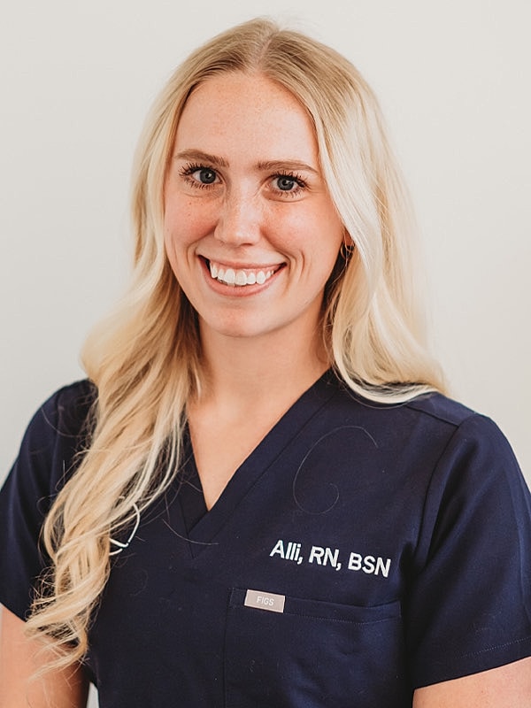 Smiling nurse in navy scrubs, professional portrait.