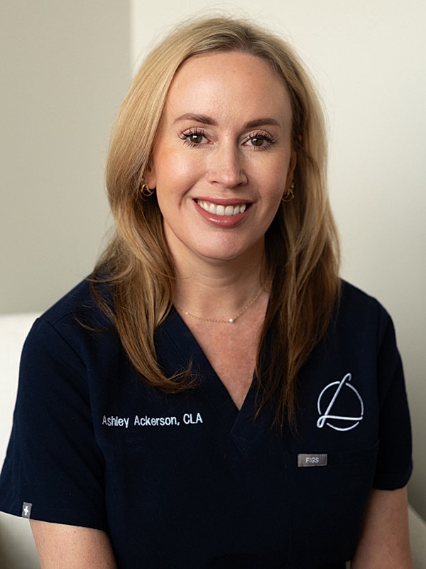 Smiling woman in a medical uniform, professional setting.