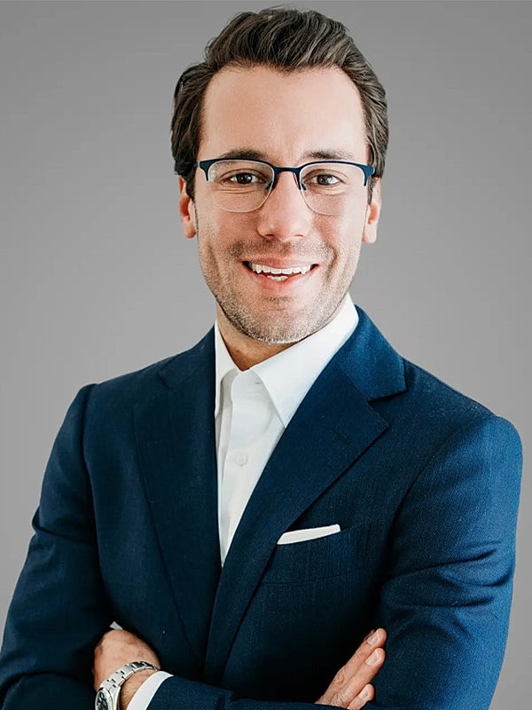 Smiling man in a suit with glasses.