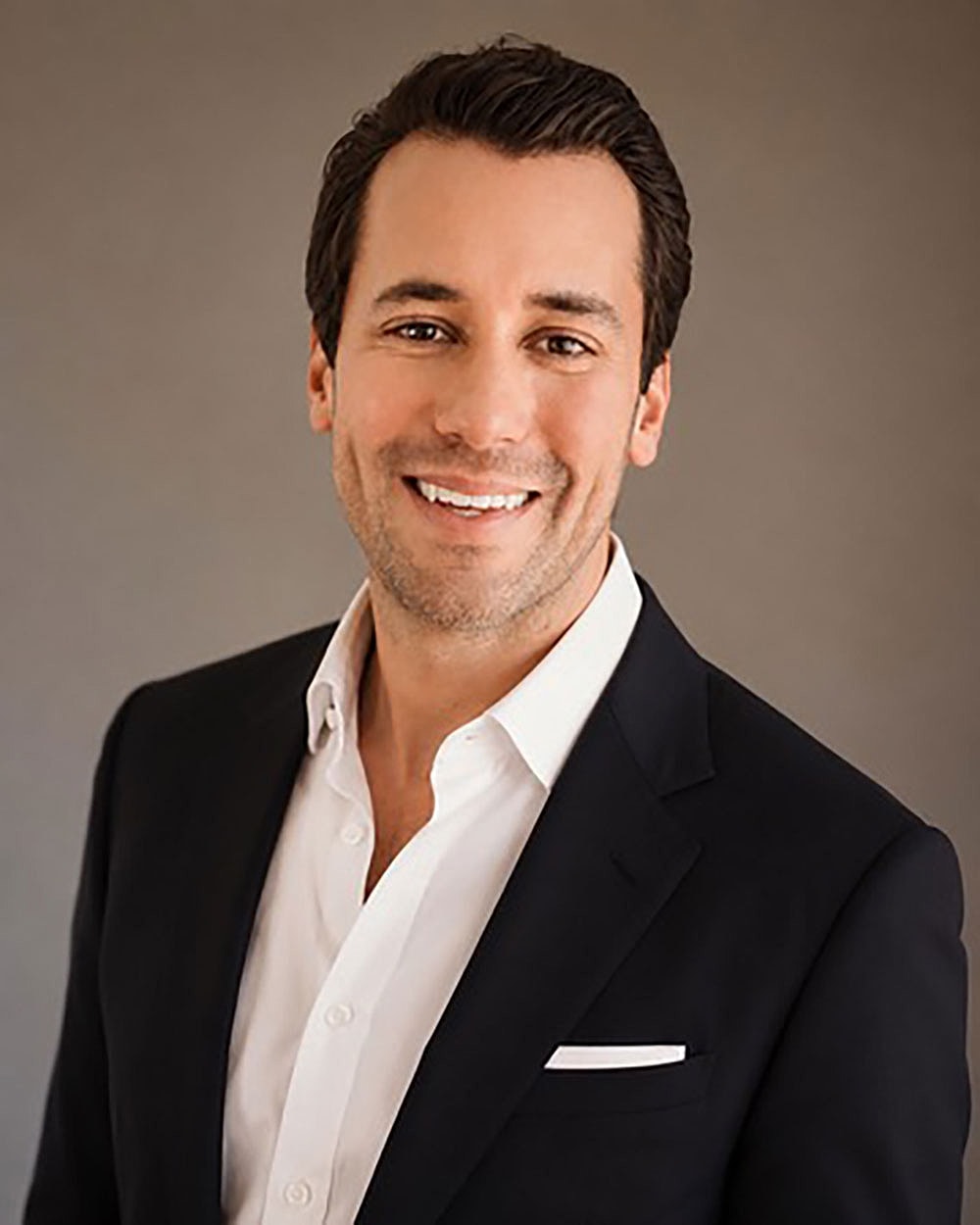 Smiling man in a blazer with white shirt.
