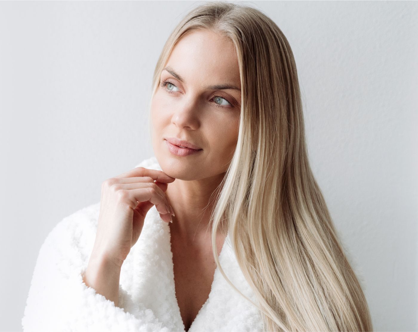 Woman in white robe thoughtfully looking away.