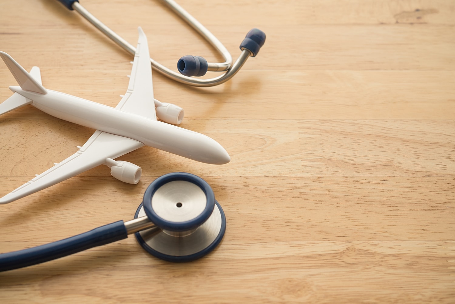 Airplane model with stethoscope on wooden surface.